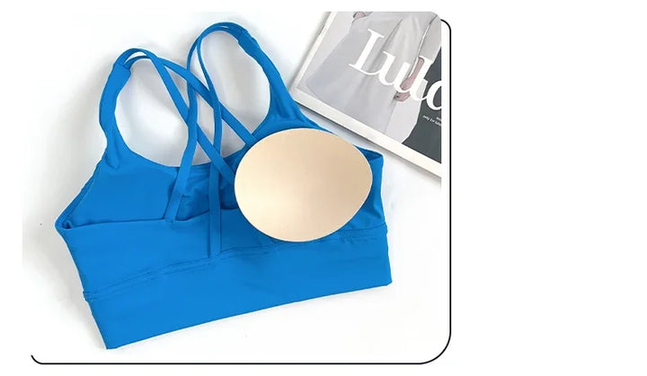 Blue sports bra with a gold circular pad on a white background