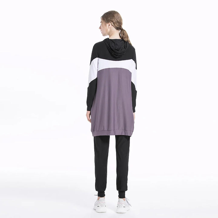 Person wearing a black, white, and gray color-blocked hoodie on a white background