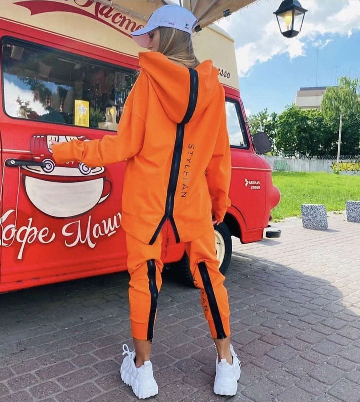 Person wearing an orange tracksuit with a red vehicle in the background