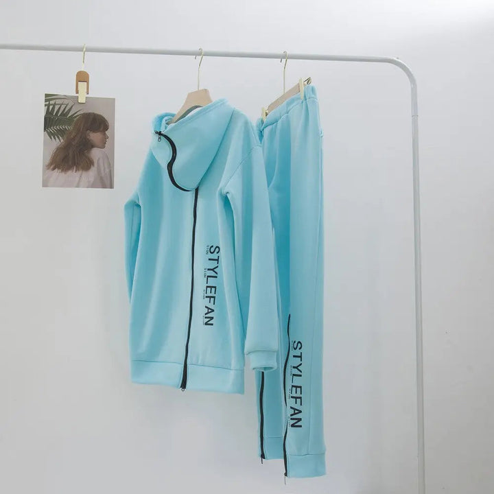 Light blue tracksuit with  on hangers against a white wall.