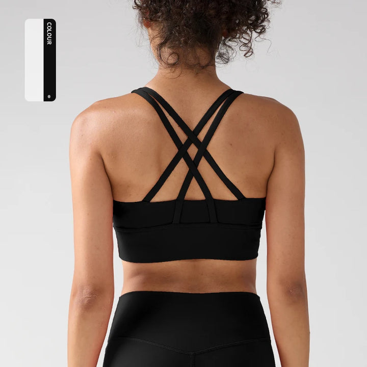 Person wearing a black sports bra with criss-cross straps on a light gray background