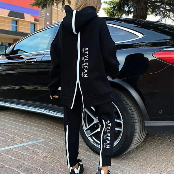 Person wearing a black tracksuit with 'STYLEFAN' branding, standing next to a black car.