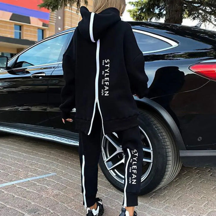 Person wearing a black tracksuit with 'STYLEFAN' branding, standing next to a black car.