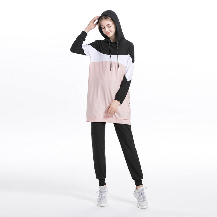 Person wearing a black, white, and pink color-blocked hoodie and pants on a white background