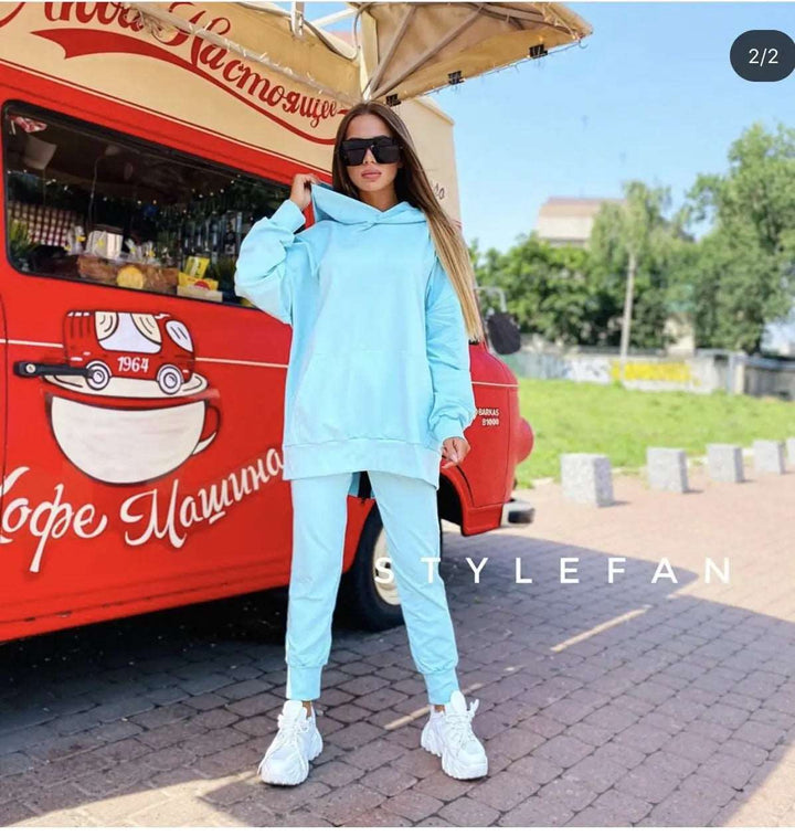 Person wearing a light blue tracksuit standing in front of a red food truck.