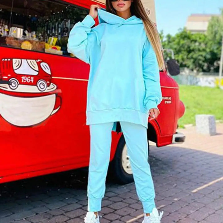 Person wearing a light blue tracksuit standing in front of a red vehicle with a coffee cup design.