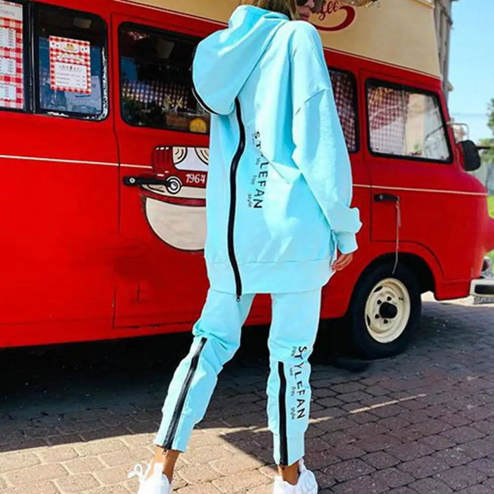 Person wearing a light blue tracksuit with 'STYLeFAN' branding in front of a red van.