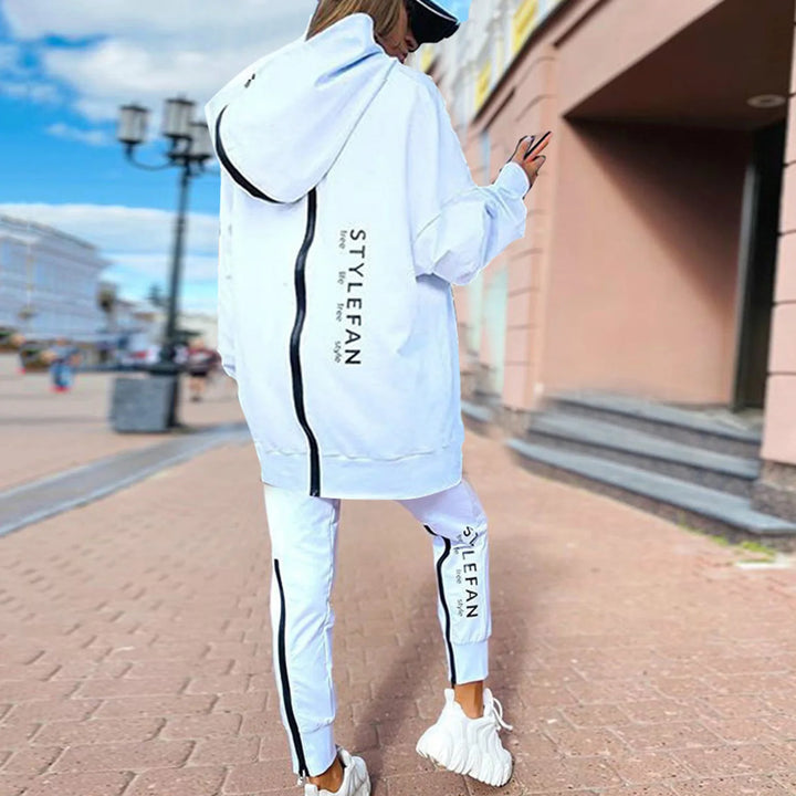 Person wearing a white tracksuit with 'white' branding on a city street.
