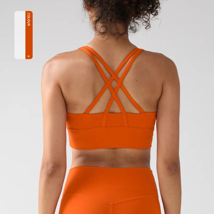 Person wearing an orange sports bra and leggings set on a plain background