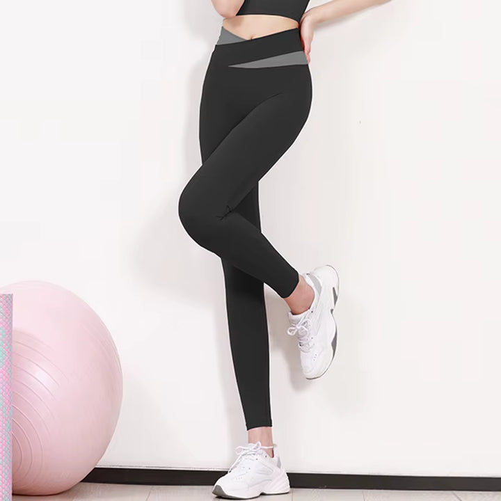 Person wearing black leggings and white sneakers with a pink exercise ball in the background.