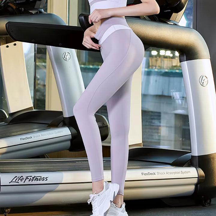 Person wearing light purple leggings and white sneakers standing on a Life Fitness treadmill.