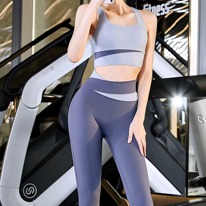 Woman in a gray sports bra and leggings standing in front of a treadmill.