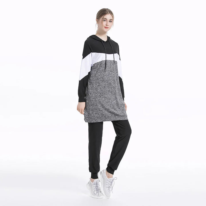 Woman wearing a black, white, and gray color-blocked dress on a white background