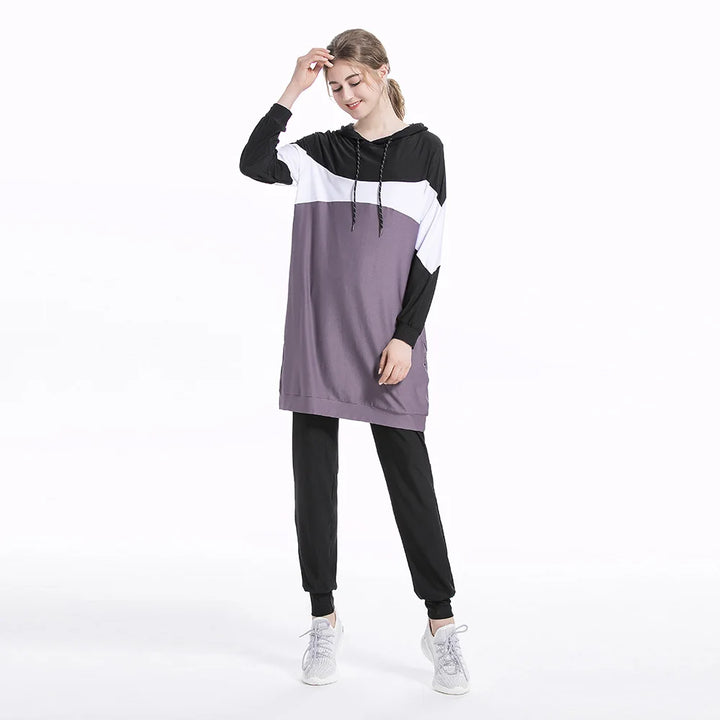 Woman wearing a black, white, and purple color-blocked hoodie and pants on a white background