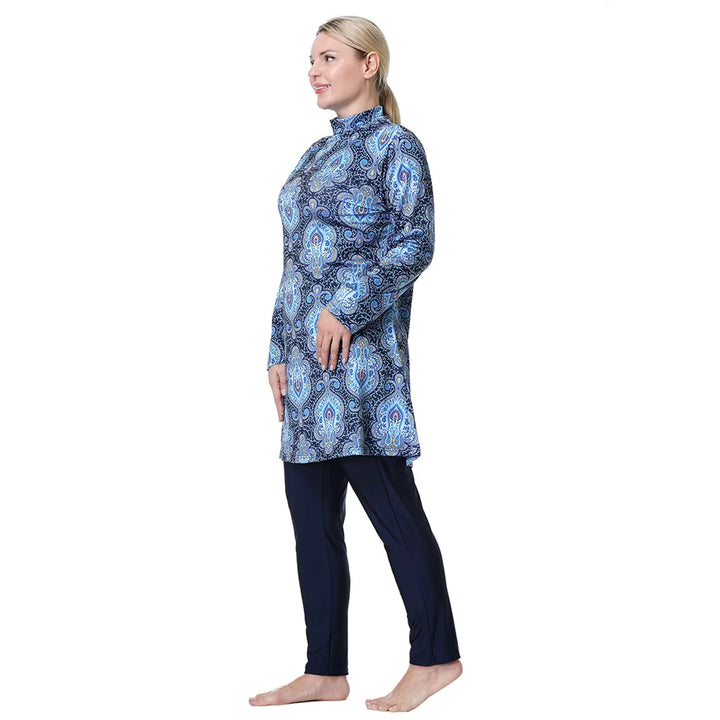 Woman wearing a blue patterned long-sleeve swimwear top and black pants on a white background