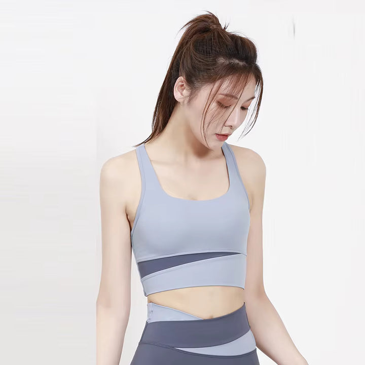 Woman wearing a light blue and gray sports bra and leggings on a white background