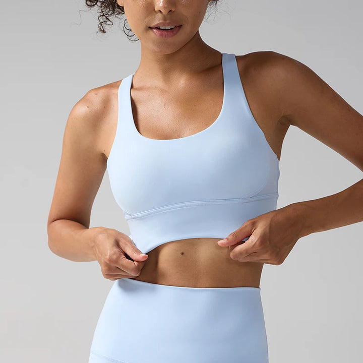 Woman wearing a light blue sports bra and leggings against a gray background