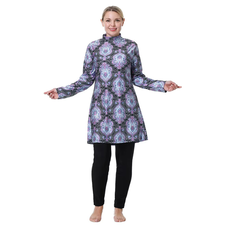 Woman wearing a patterned long-sleeve top and black leggings modest swimwear on a white background