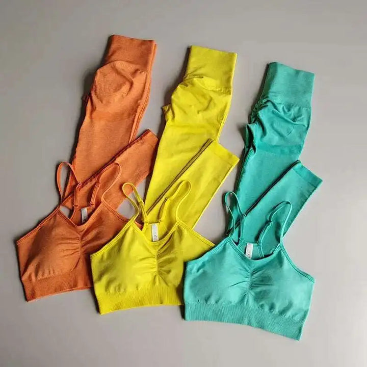 Three colorful sports bras in orange, yellow, and green on a gray background