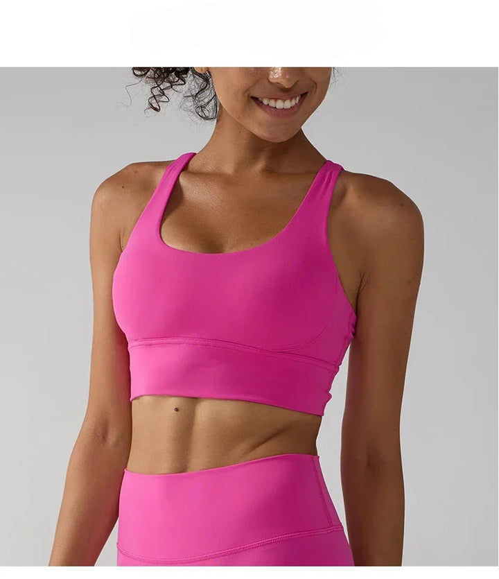Person wearing a bright pink sports bra and leggings on a gray background