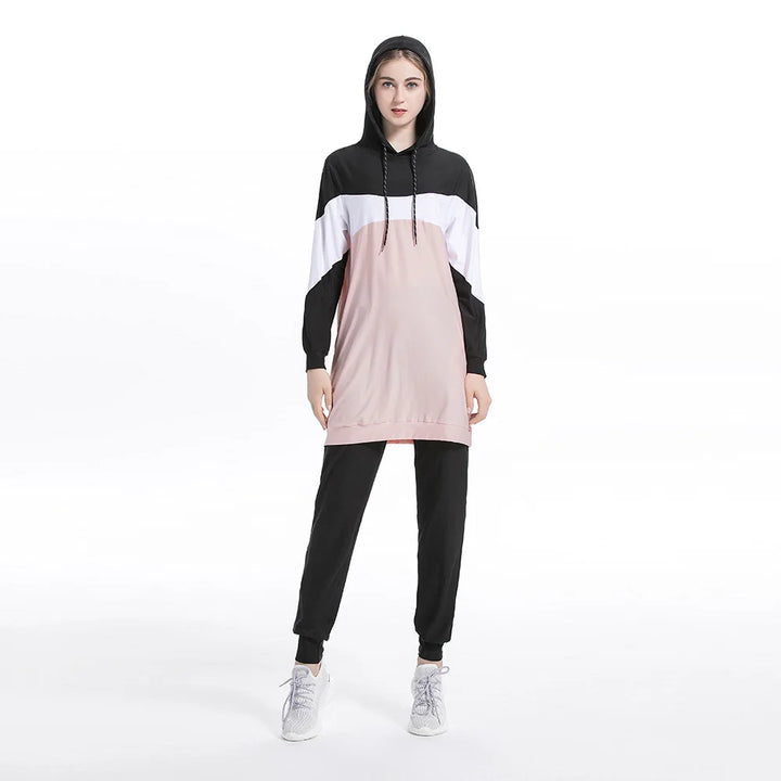 woman wearing a black, white, and pink hoodie with matching pants on a white background